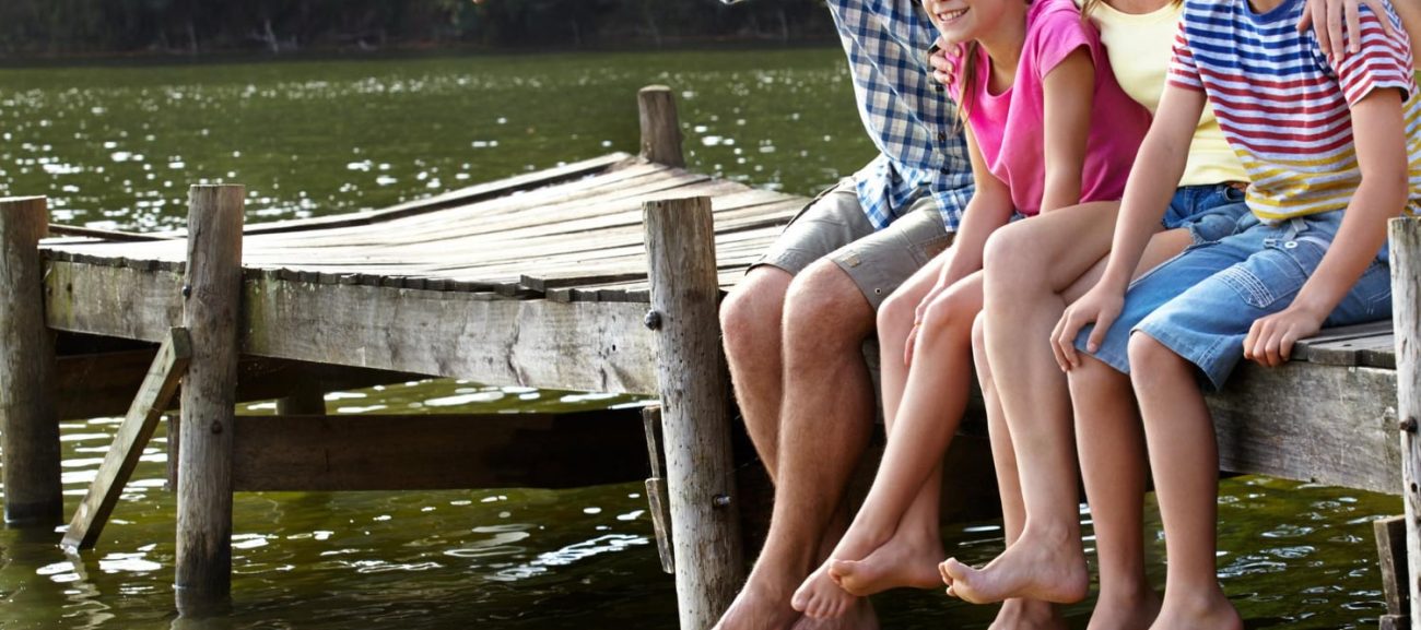 Family enjoying a beautiful Manitoba cottage waterfront with dock at sunset