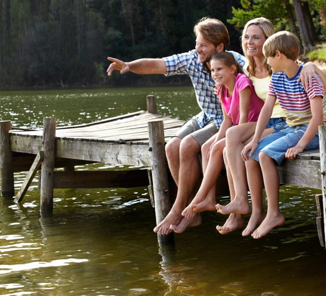 Family enjoying a beautiful Manitoba cottage waterfront with dock at sunset Family enjoying a beautiful Manitoba cottage waterfront with dock at sunset