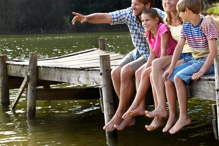 Family enjoying a beautiful Manitoba cottage waterfront with dock at sunset Family enjoying a beautiful Manitoba cottage waterfront with dock at sunset
